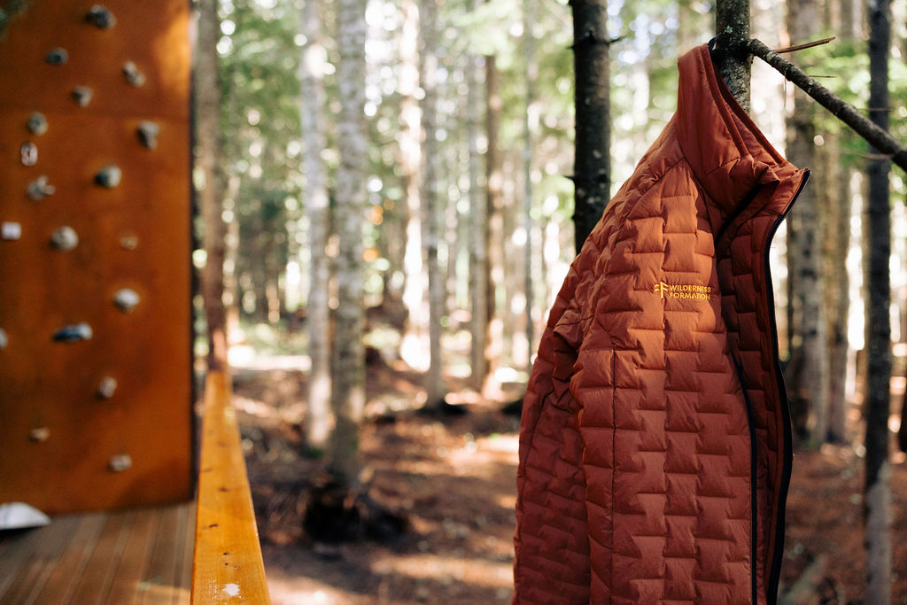 A Wilderness Formation puffy hanging on a tree at Snoqualmie Pass, with the climbing wall in the background